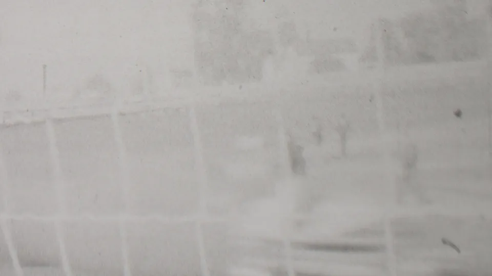 Overexposed frame from the 1937 Trenton home-movie racing footage, with faint fence geometry and indistinct trackside background visible through film haze.