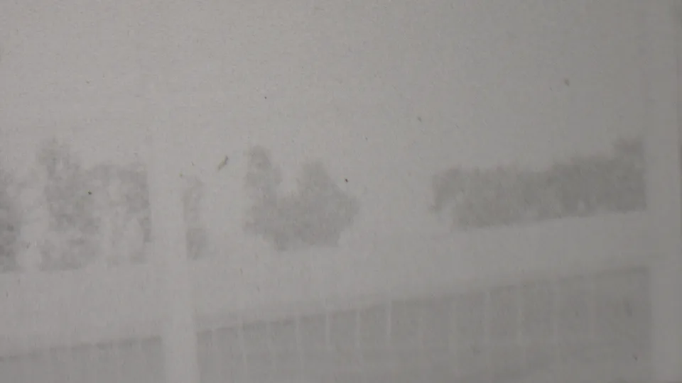 A washed-out frame shows the outdoor track area and faint barrier lines, with background shapes softened by exposure and film wear.