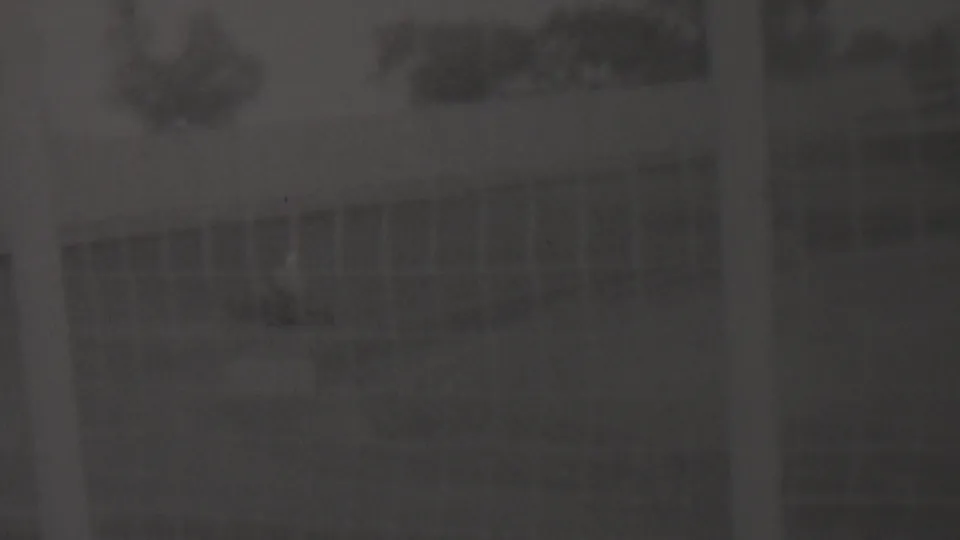 Final dim frame from the 1937 Trenton 8mm clip, showing a barely legible outdoor track setting with faint fence or building lines and no clearly identifiable people or markings.