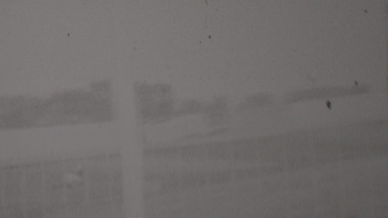 A heavily obscured 1937 home-movie frame from the supplied Trenton, New Jersey clip shows faint outdoor structures and trees through grain, dust, and low contrast.