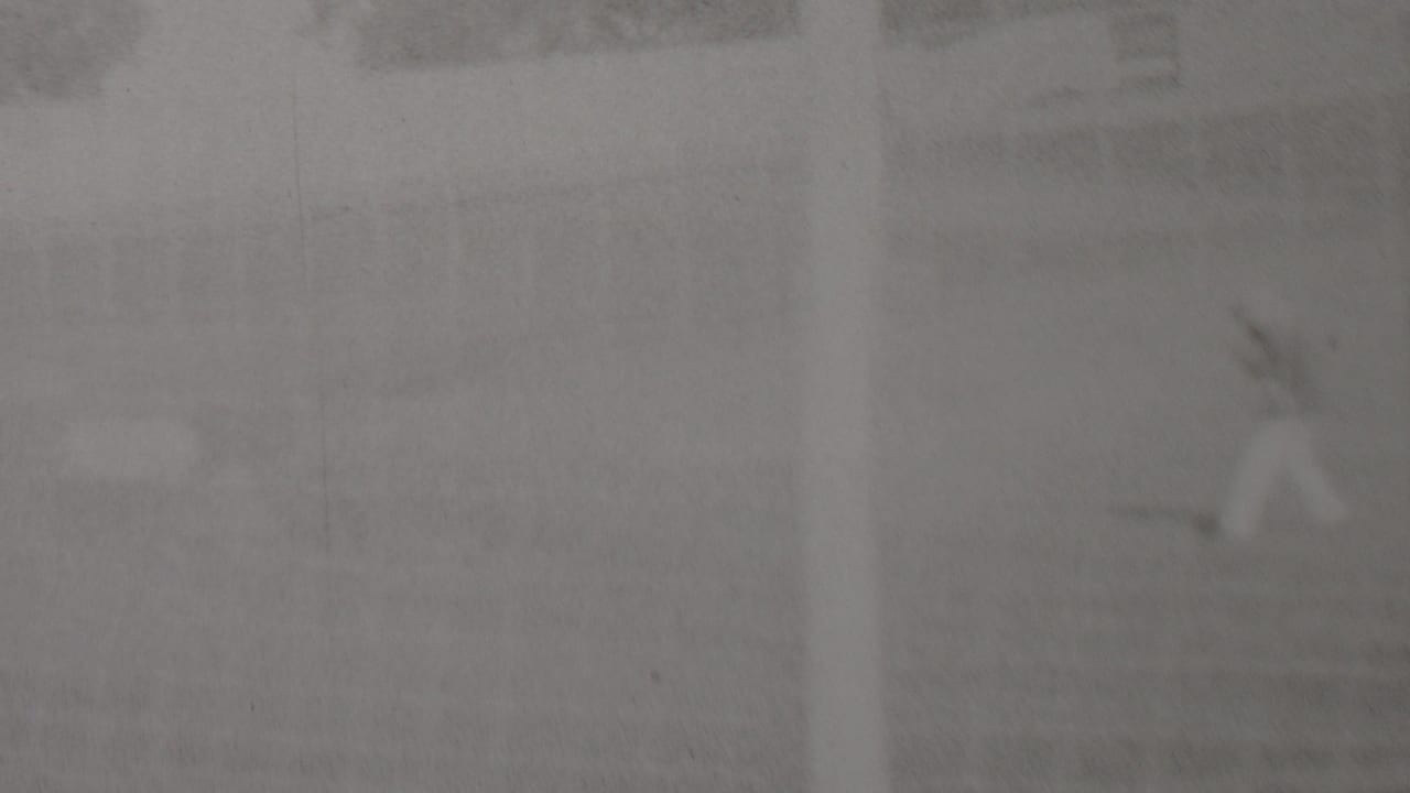 Distant motorcycle rider passing through a soft, overexposed track scene.