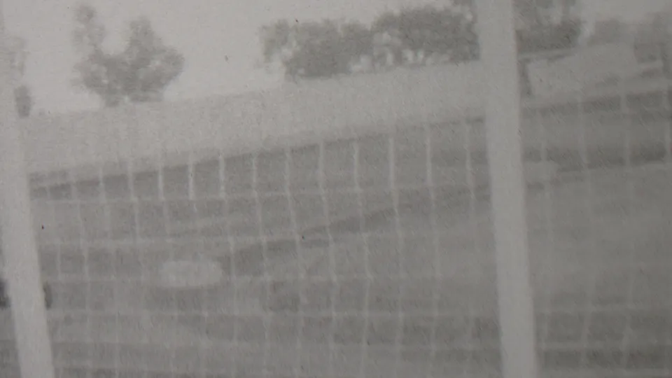 Soft 1937 8mm frame from the Trenton, New Jersey metadata showing pale trackside fencing or a structure with trees faintly visible beyond it.