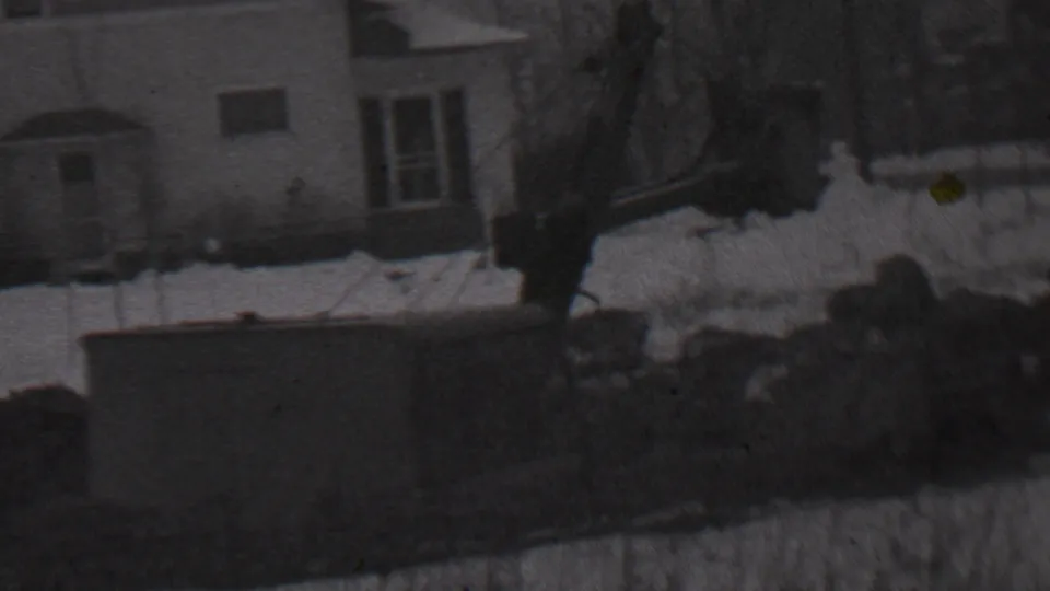 Black-and-white 8mm frame from Trenton in 1937 showing a snowy residential facade, windows, bare trees, and shadowed objects near the camera.