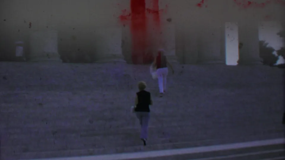 1969 home-movie frame from Washington DC showing two women ascending wide stone steps toward a neoclassical monument with massive columns.