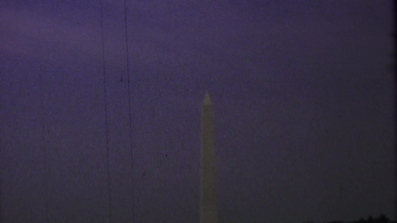 Washington Monument faintly visible against a dark purple dusk sky.