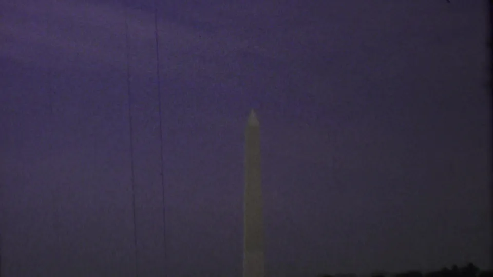 Dim 1969 8mm view of the Washington Monument standing against a purple evening sky with visible vertical film wear.
