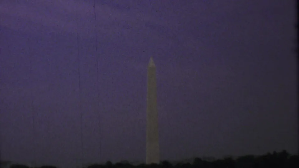Washington Monument seen from a visitor vantage in Washington, DC, with a dark treeline at the bottom of the 1969 8mm frame.