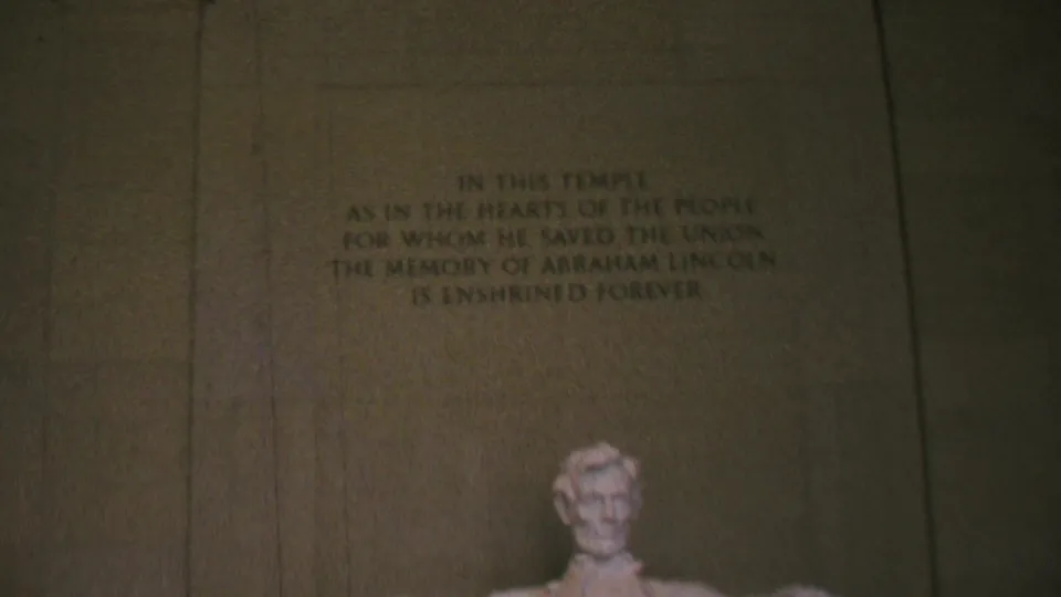 Handheld 1969 8mm view of the Lincoln Memorial inscription, with the seated Abraham Lincoln statue partly visible at the bottom of the frame.