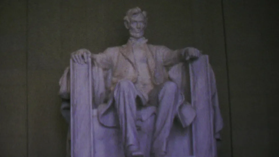 Zoomed-in 8mm view of the seated Abraham Lincoln statue in Washington, DC's Lincoln Memorial, framed against the dark interior wall.