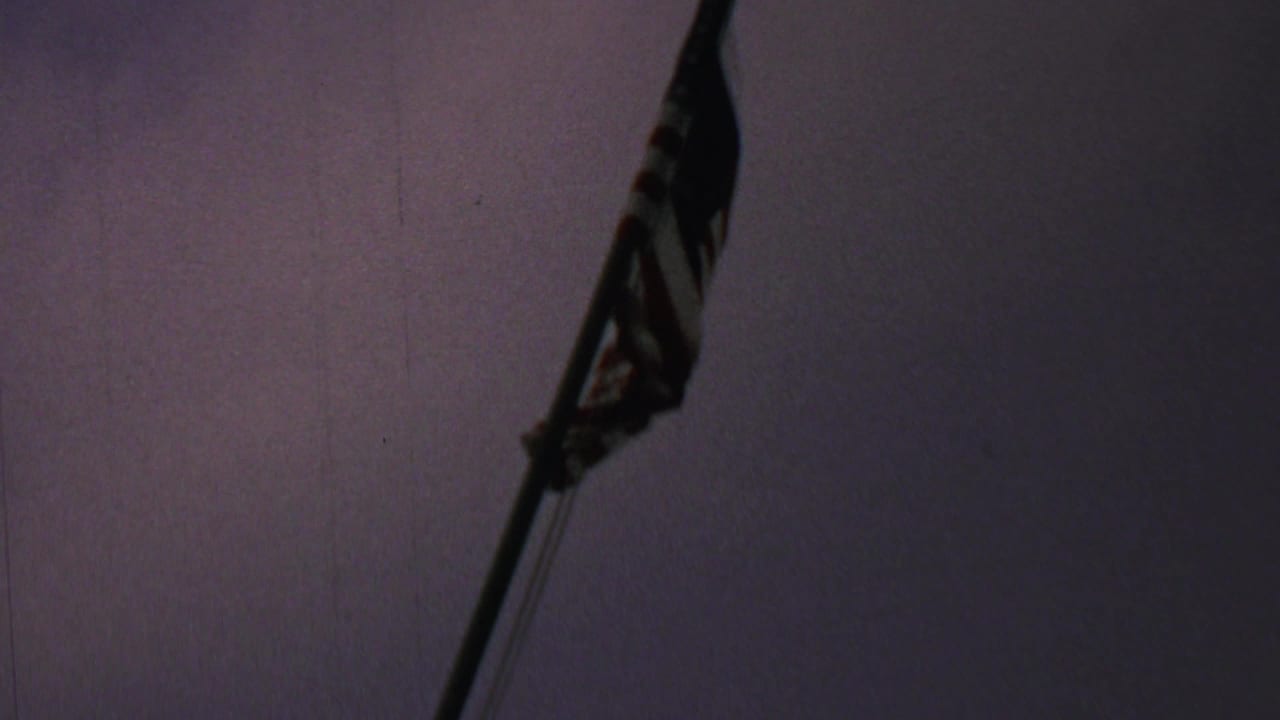 A U.S. flag on a tall pole appears in soft silhouette against a dark purple evening sky in 1969 home-movie footage from Washington DC, according to the supplied metadata.