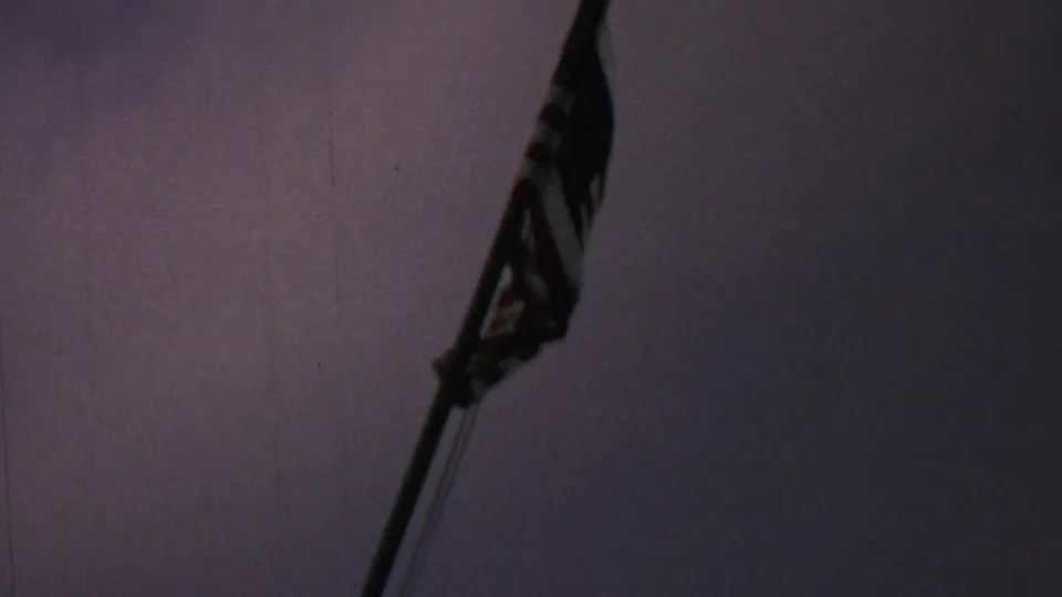 A U.S. flag on a tall pole appears in soft silhouette against a dark purple evening sky in 1969 home-movie footage from Washington DC, according to the supplied metadata.