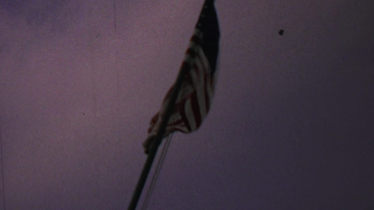 American flag near the top of a pole against a dim purple sky.