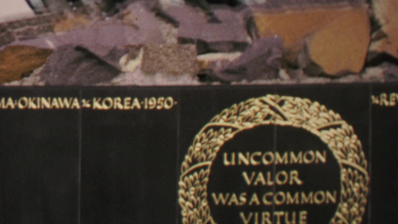 1969 Washington DC 8mm frame showing a close-up of a black memorial plaque with gold lettering, partial Iwo Jima, Okinawa, and Korea text, and the edge of a laurel wreath inscription.