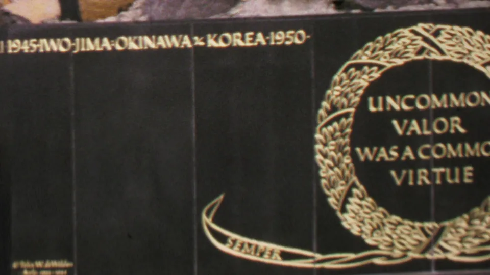 1969 Washington DC 8mm frame showing a handheld close-up of the memorial plaque, with Iwo Jima, Okinawa, and Korea text along the top and the central laurel wreath inscription visible.