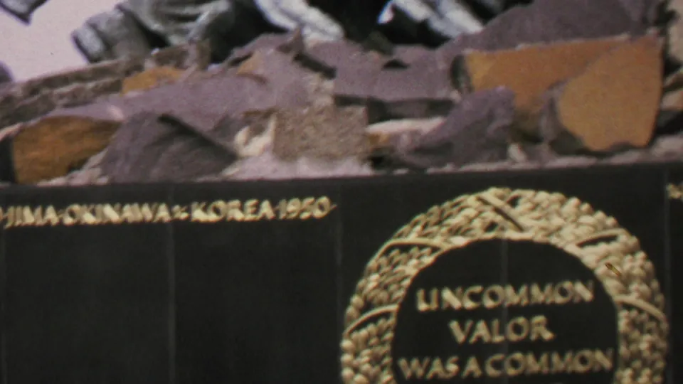 1969 Washington DC 8mm frame showing a cropped section of the memorial plaque with gold campaign lettering, part of the laurel wreath text, and sculptural stone forms above.