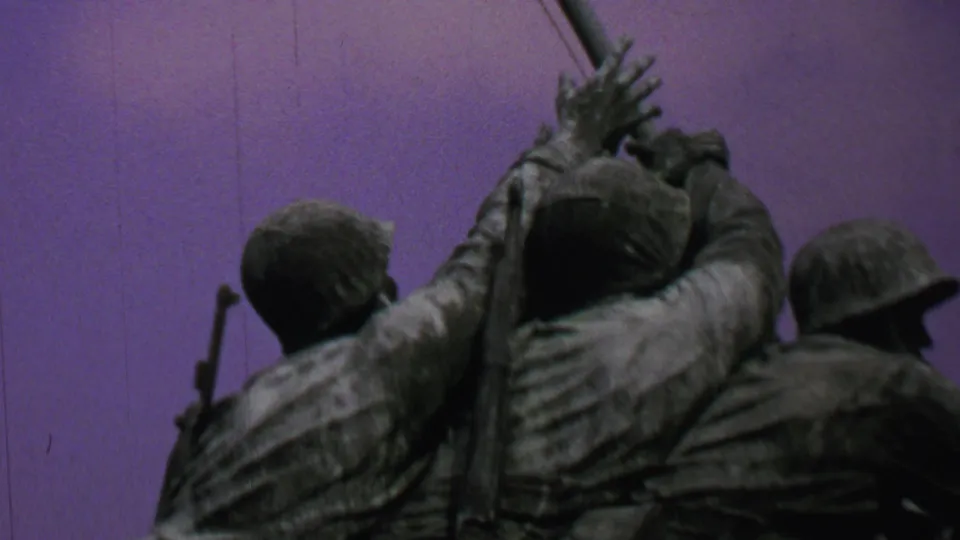 1969 Washington, DC frame of the Iwo Jima Memorial with multiple sculpted Marines clustered around the flagpole, shot upward against a purple-tinted sky.