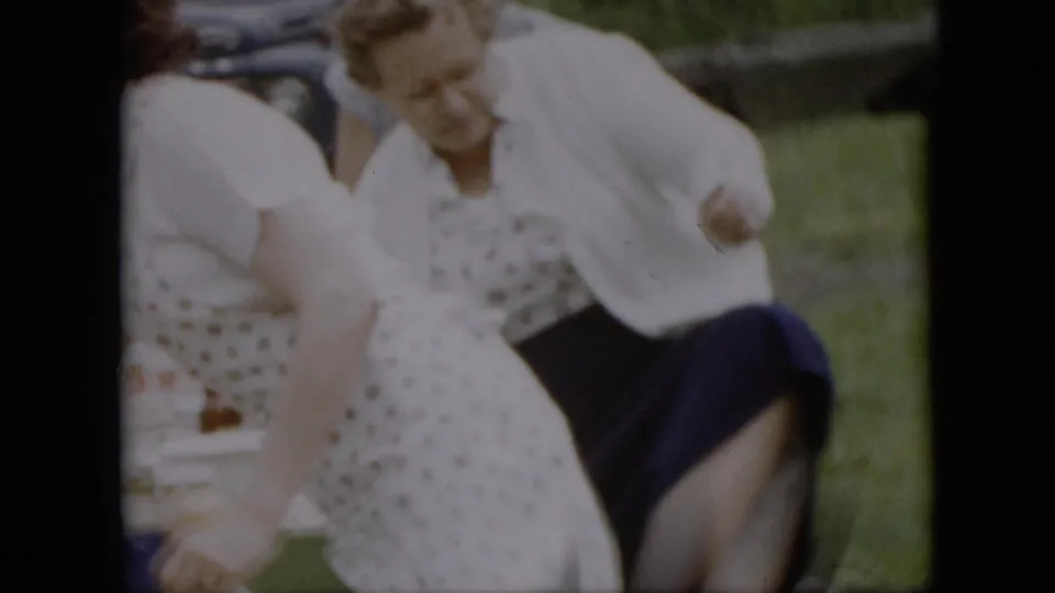 Adult women in midcentury dresses, aprons, and skirts move around a picnic table with containers and bottles during an outdoor gathering in Pennsylvania, according to clip metadata.