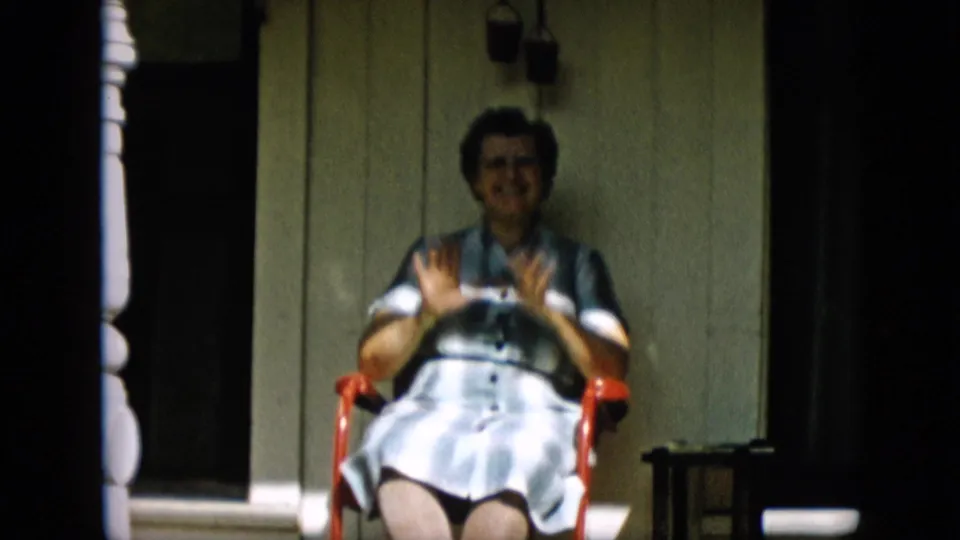 In the lower-left frame, the older woman appears to smile and lift both hands in a playful gesture while seated in the red chair against the porch wall.