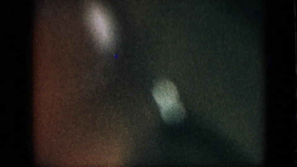 Grainy 1957 8mm home-movie frame with green and brown color cast, soft pale light flares, and no clearly identifiable subject in the visible still.
