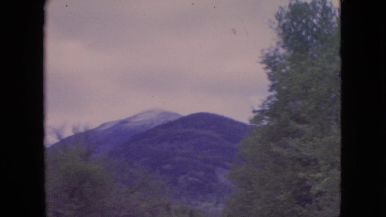 Mountain ridge and trees viewed through a dark vertical frame edge.