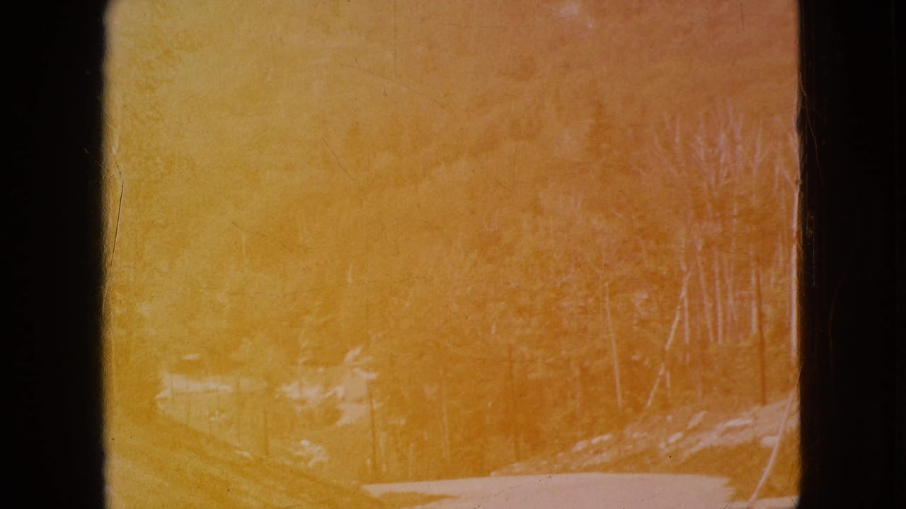 A heavily faded 1964 8mm frame from the Niagara Falls, New York reel shows a yellow-orange tinted outdoor landscape with dark film borders and faint wooded shapes.