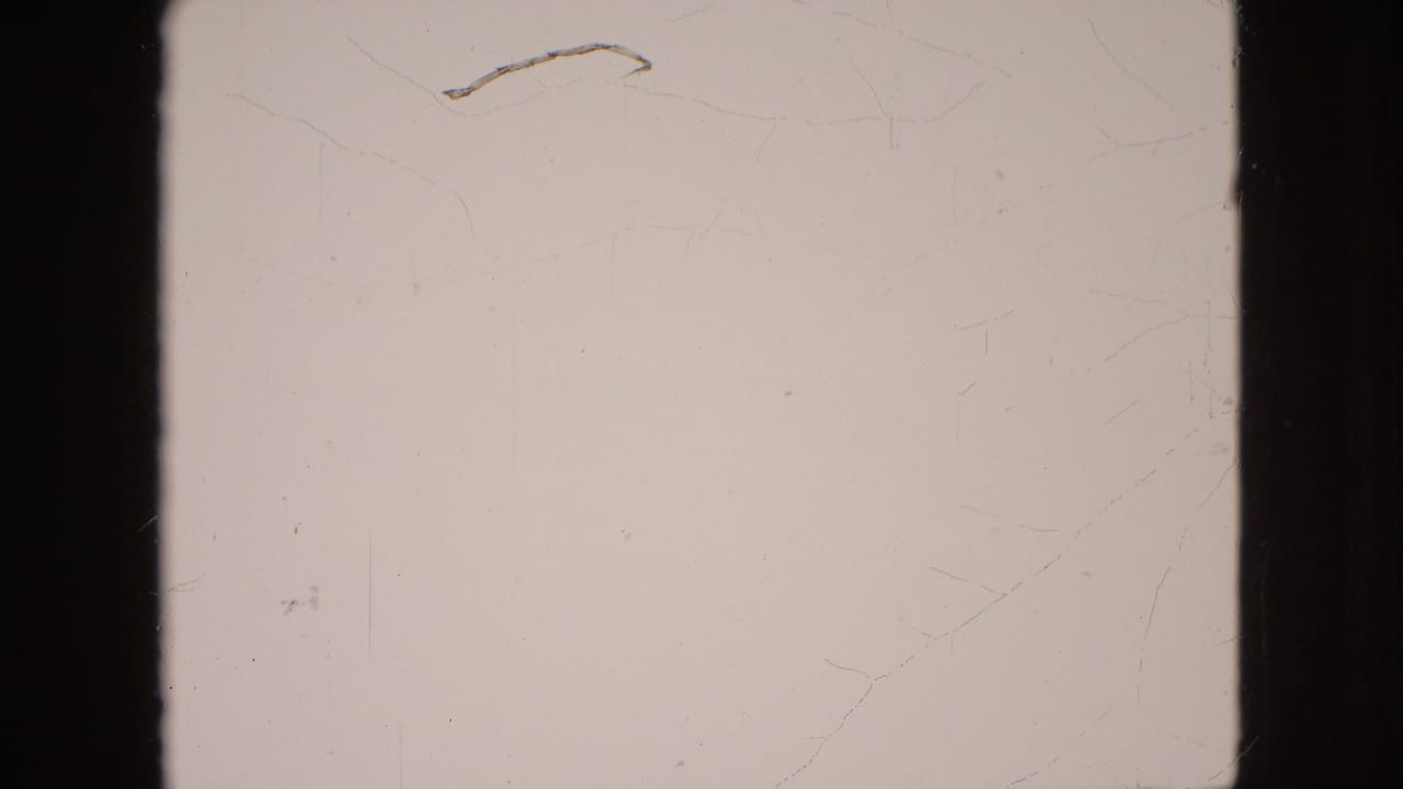 Mostly blank pale film frame with dark border and light scratches.