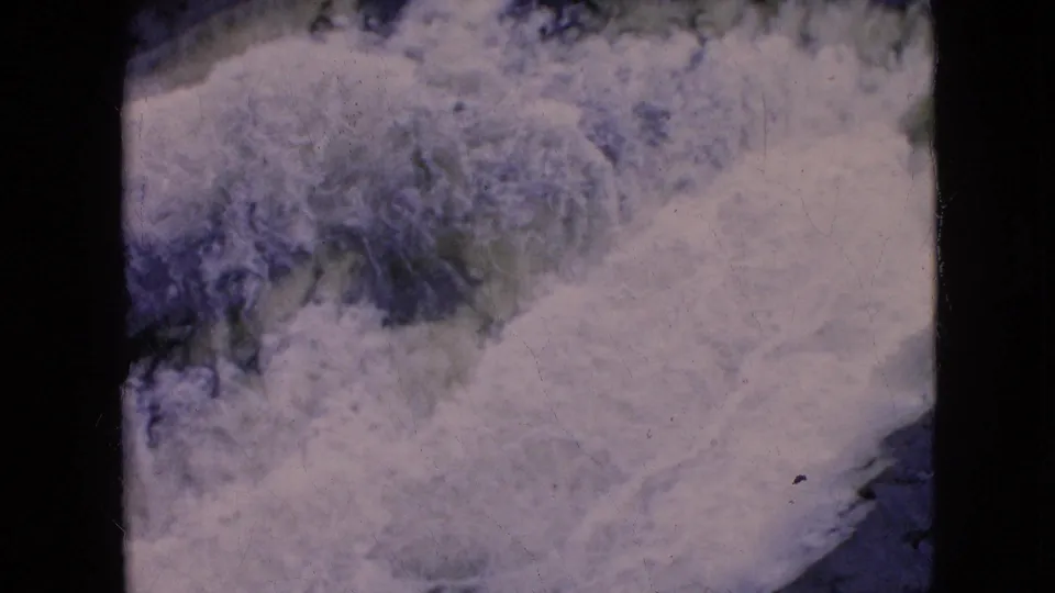 1964 8mm frame of Niagara Falls showing dense white spray and rushing water against a dark blue-purple surface near the end of the clip.