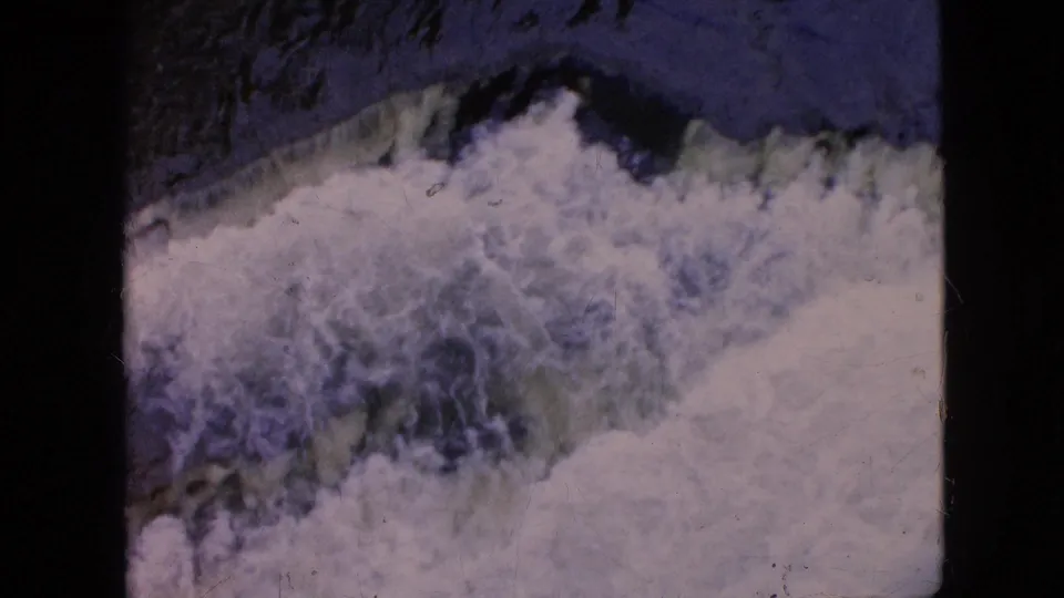 1964 8mm Niagara Falls, New York frame with foaming white water, a dark blue-green channel, and visible archival film texture.