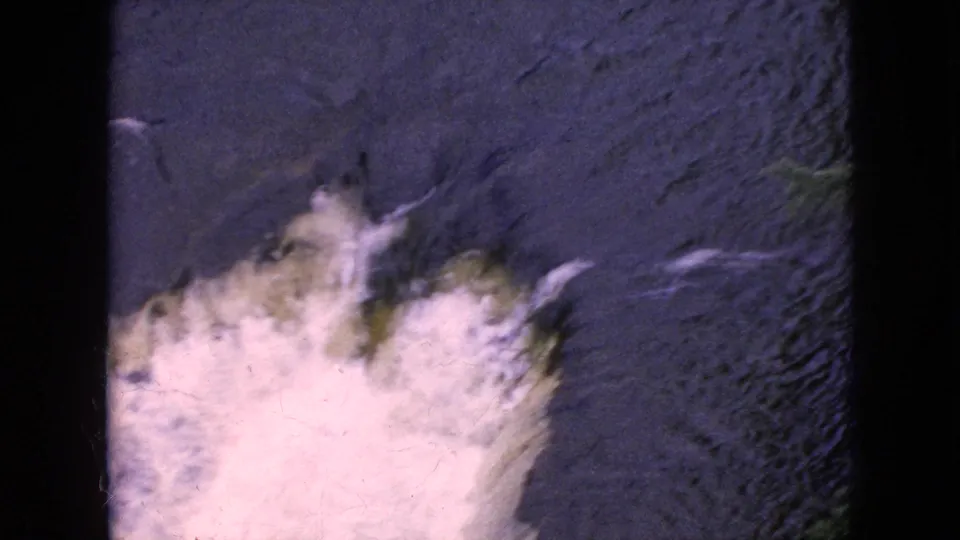 1964 8mm home-movie frame from the Niagara Falls, New York area showing frothy white rapids churning through dark stream water with visible film grain and borders.