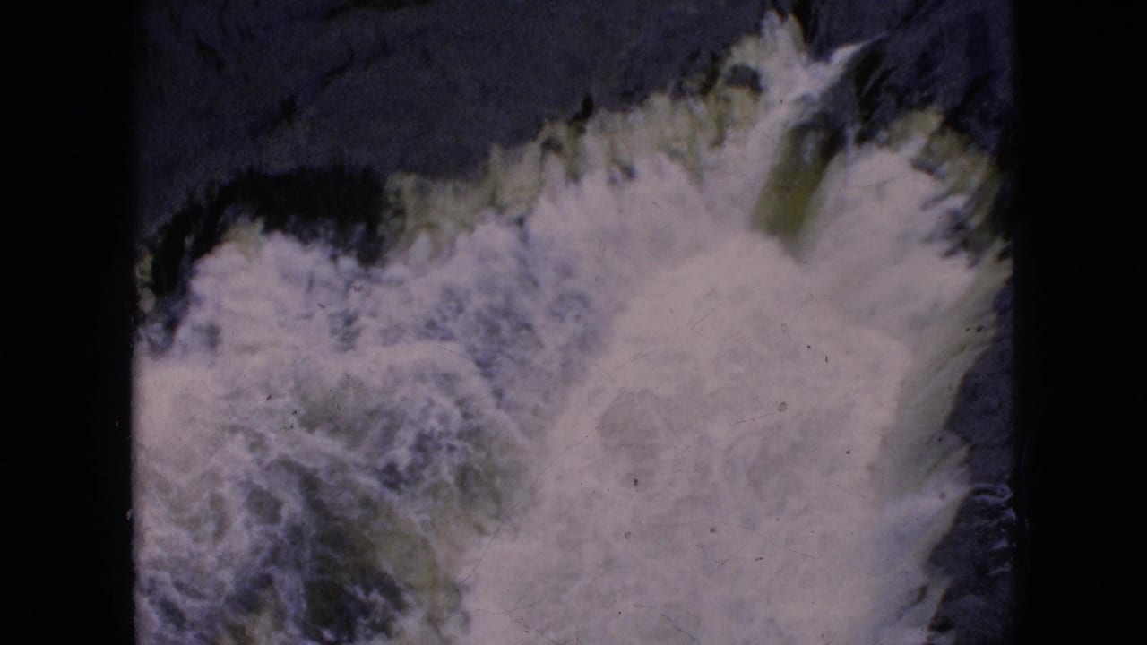 1964 8mm Niagara Falls footage showing frothy white water churning over dark rock, with the scanned film edge visible around the frame.