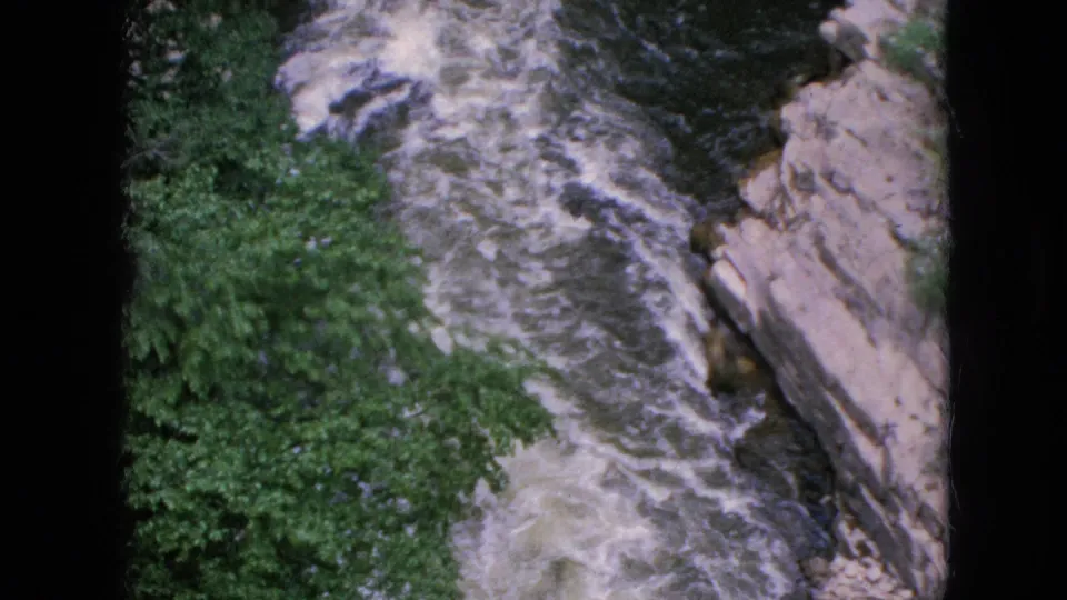 Vintage 8mm frame of turbulent river rapids flowing downstream through a narrow rock-lined canyon in the Niagara Falls, New York area.
