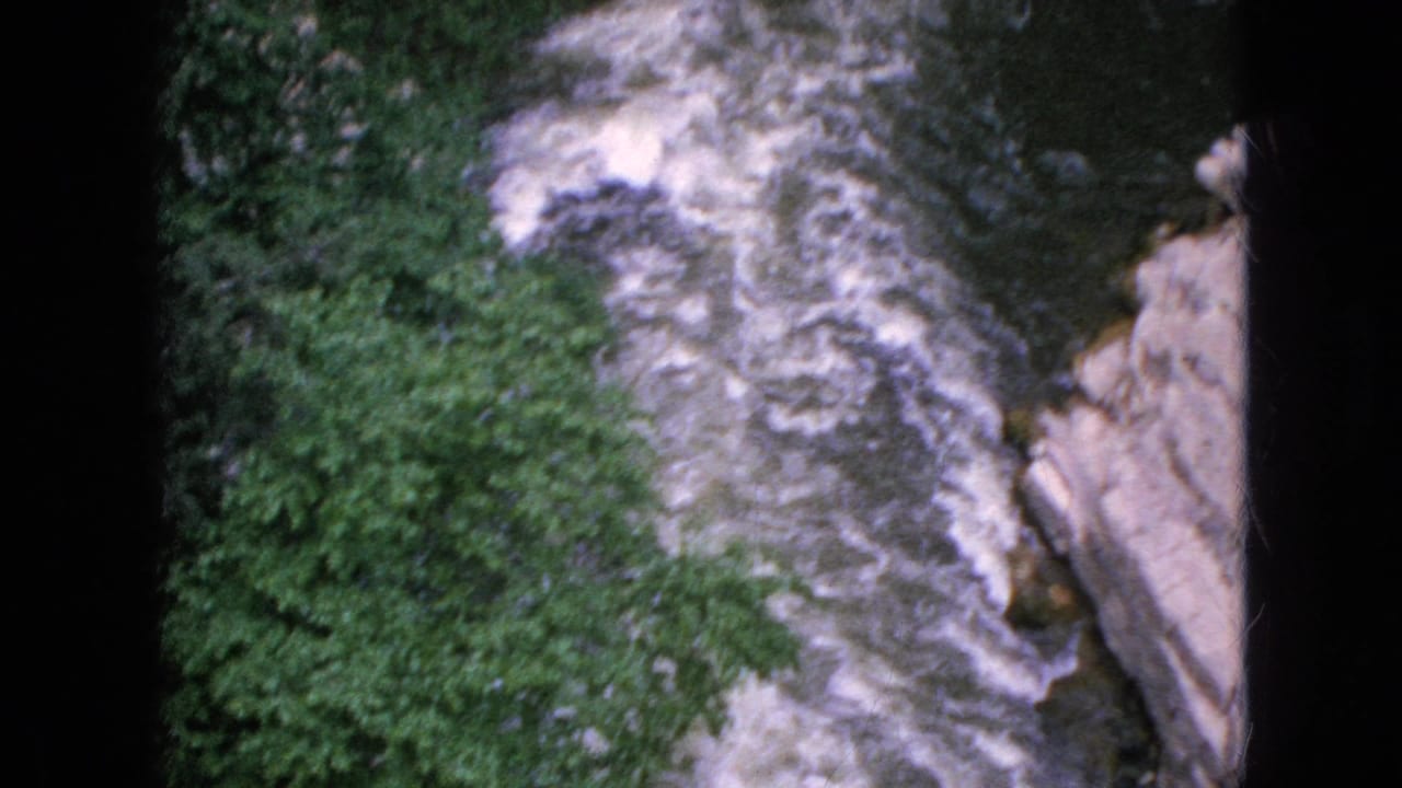 Rapids rush between foliage and pale rock walls from a high vantage point.