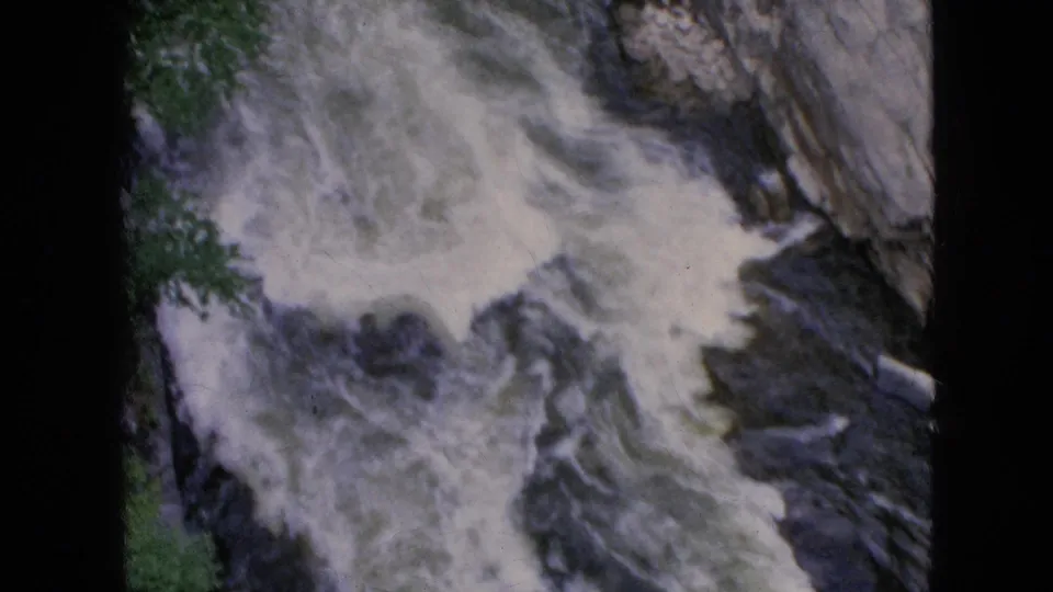 1964 Niagara Falls, New York frame showing a foamy section of rapids churning against dark rock with a pale gorge wall at the right.