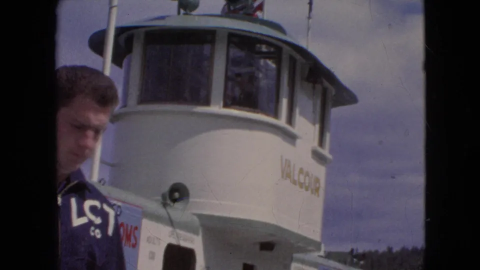 The young man is partly cropped at the side of the frame as the white Valcour ferry pilothouse, loudspeaker, and deck structure fill the background.