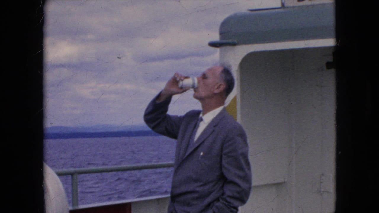 Adult man tilts a white paper cup to drink while standing near the boat railing.