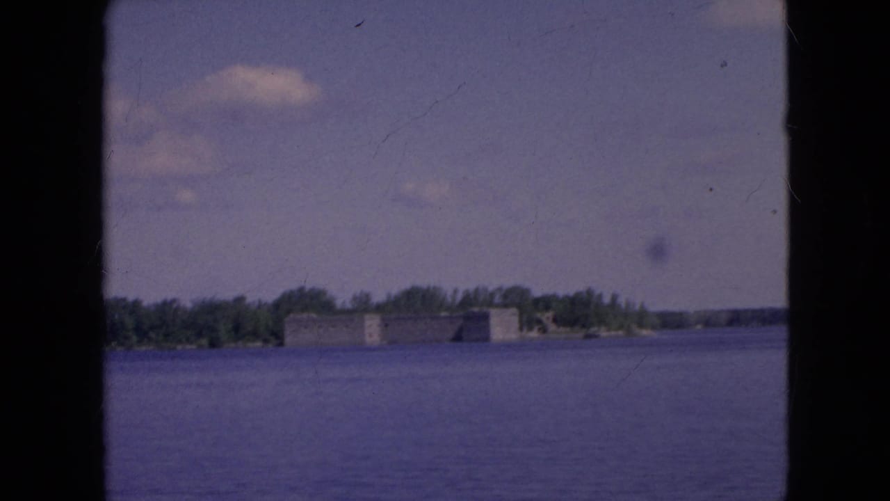 Wide river view with a distant fort-like building and trees along the shore.