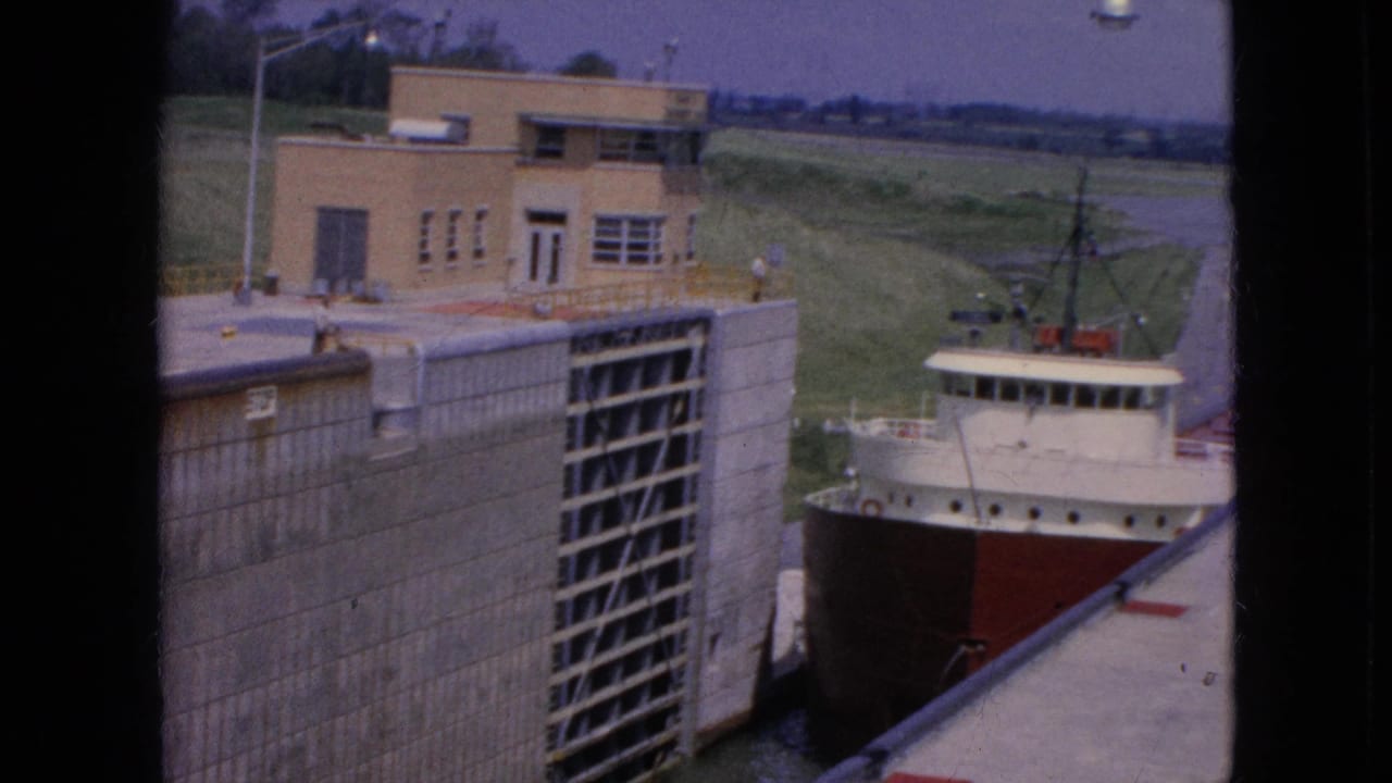 Ship bow and superstructure alongside the open lock gate.