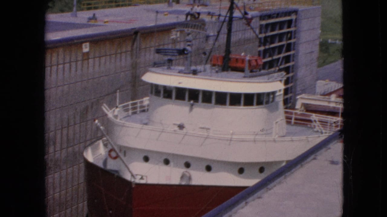 Freighter wheelhouse and bow framed against a concrete lock wall.
