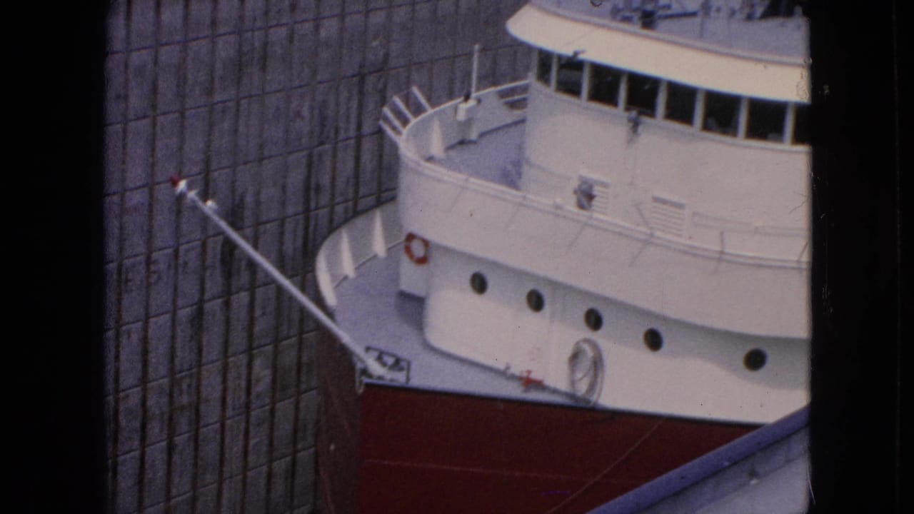 Close view of a freighter bow pressed near a tall concrete lock wall.