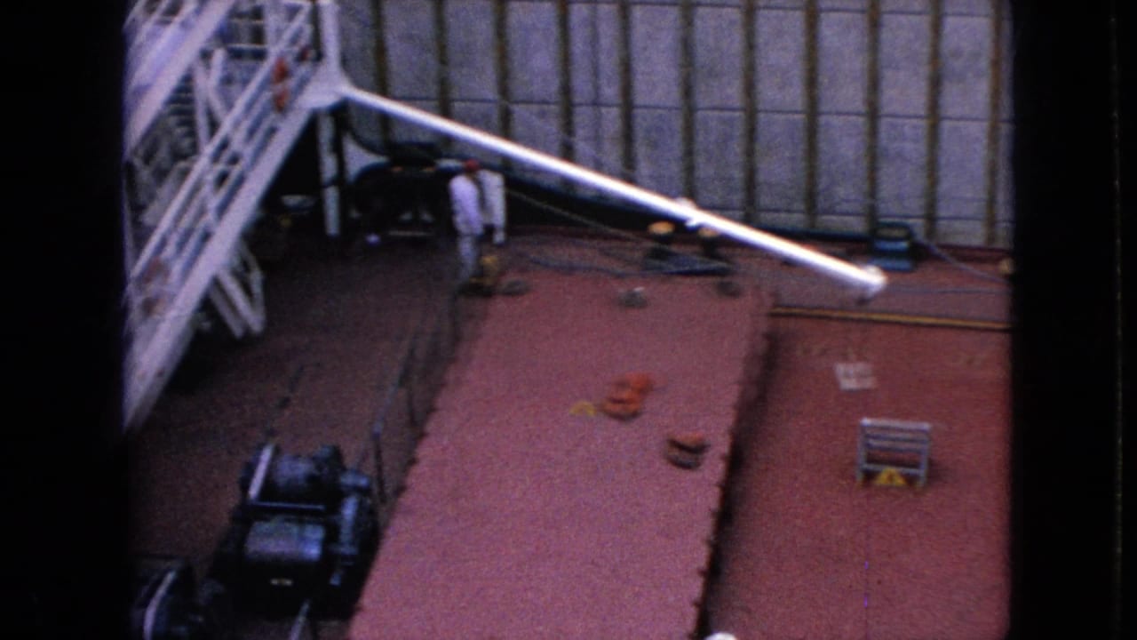 High-angle 1960s 8mm view of the Cason J. Callaway deck inside a Great Lakes lock, showing a red deck, white boom, a worker, ladders, and tall walls.