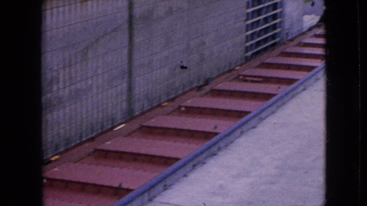 Red deck sections running along a concrete wall with a metal grate visible at the right.