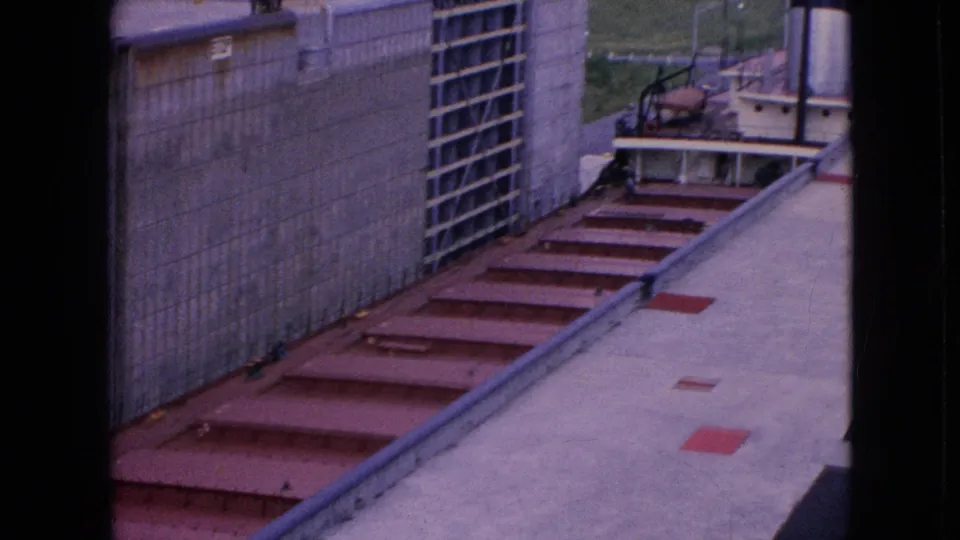 1964 Niagara Falls, New York home-movie view looking down along a concrete lock wall with red-painted metal steps and part of a tugboat visible beyond them.