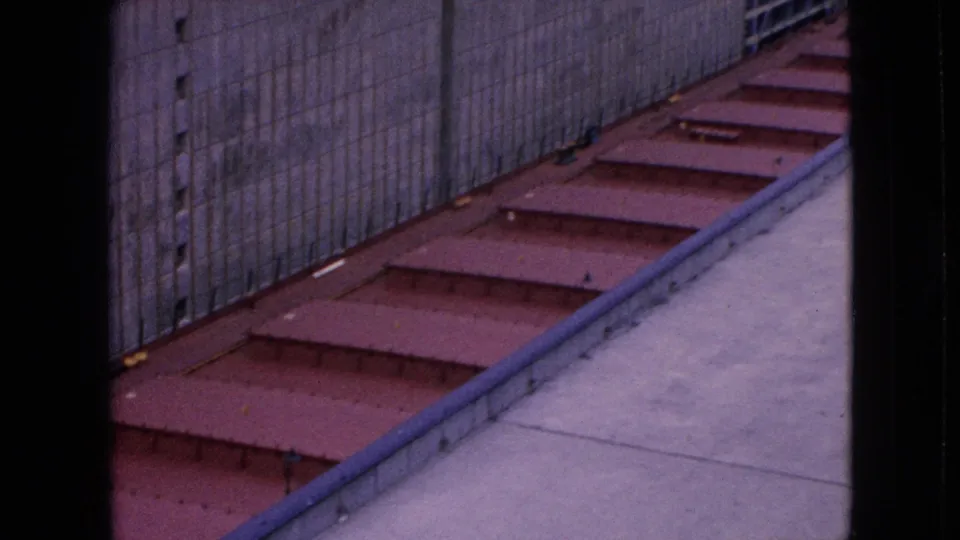 1964 Niagara Falls, New York frame showing a tighter elevated look at red-painted metal steps or deck panels running alongside a concrete lock wall and pale paved walkway.