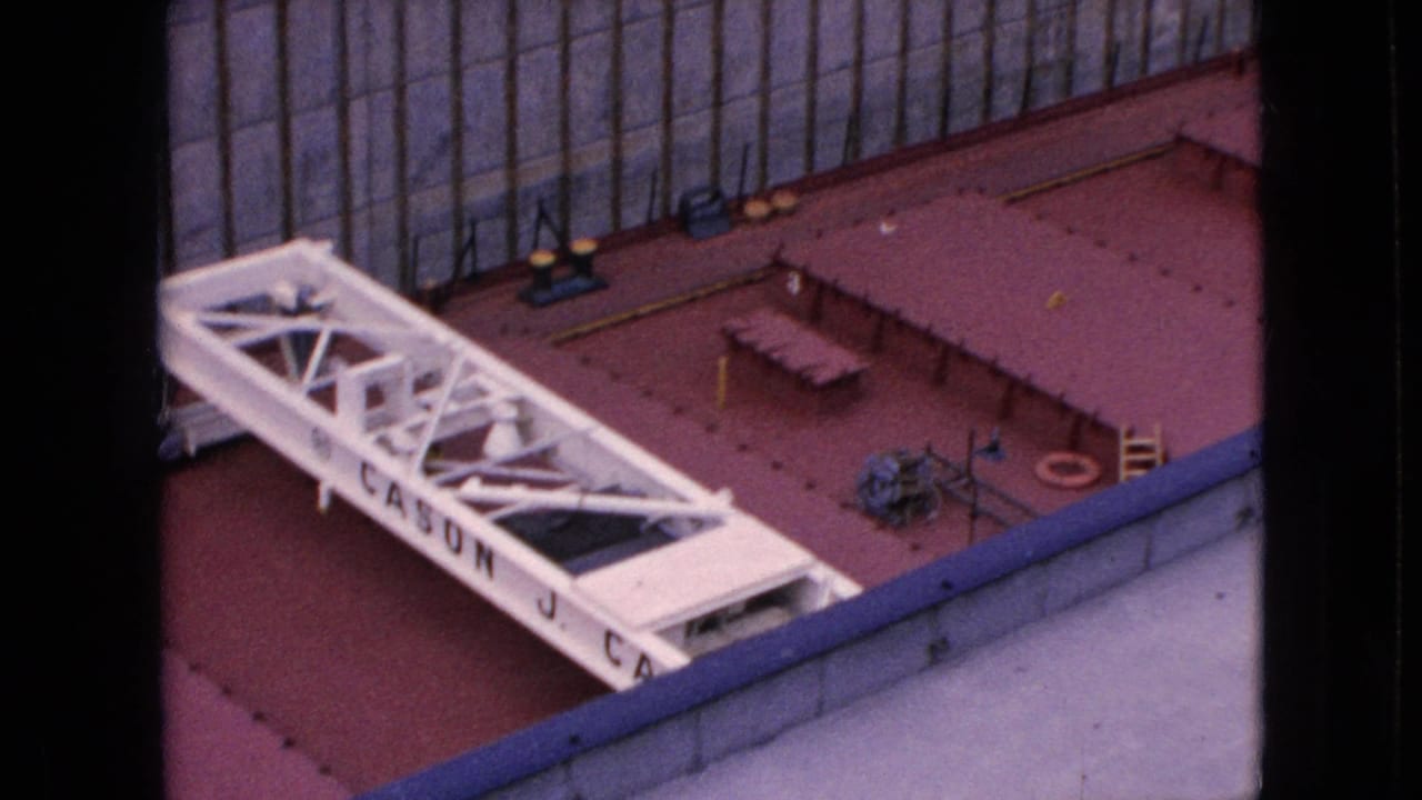 White vessel superstructure and equipment on a red deck near a tall concrete dock wall in the 1964 Niagara Falls footage.