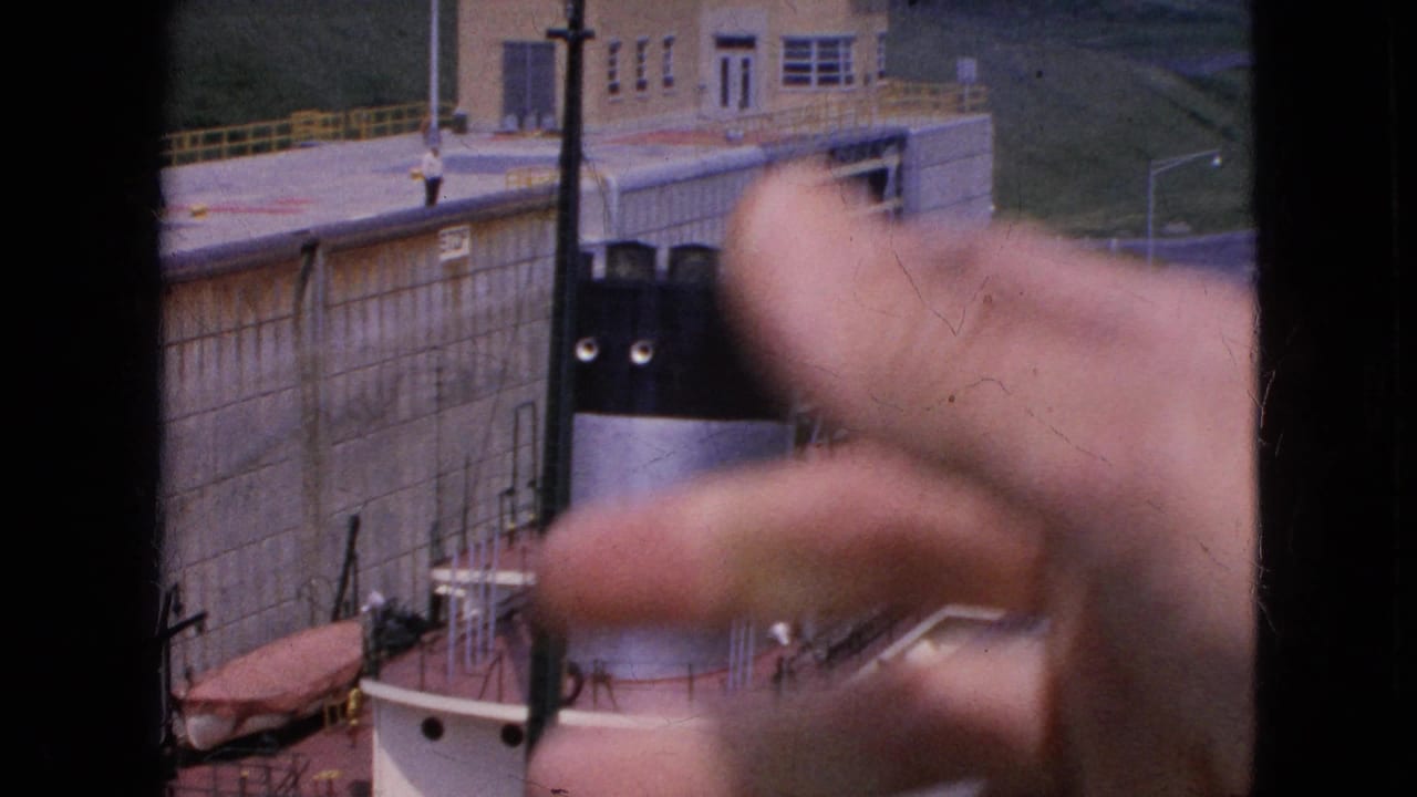 A foreground hand points across 1964 home-movie footage of a ship beside a tall concrete lock wall at Niagara Falls, New York.
