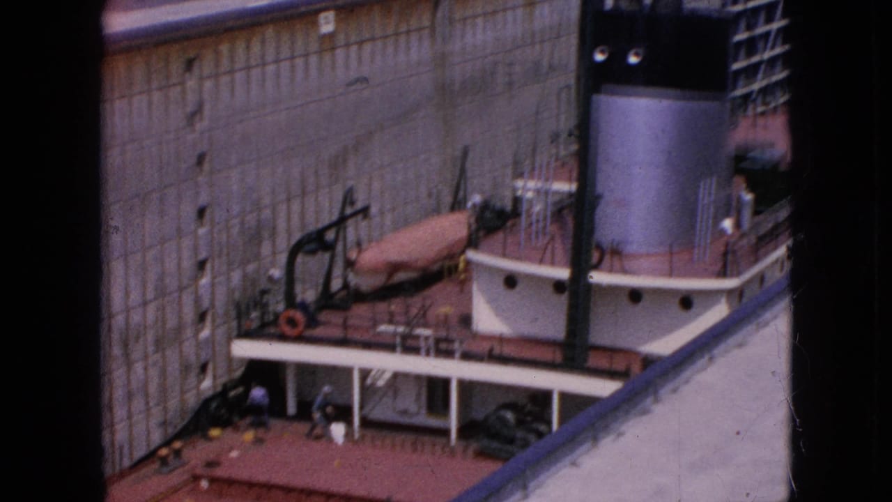 Ship deck and smokestack beside a tall concrete lock wall.