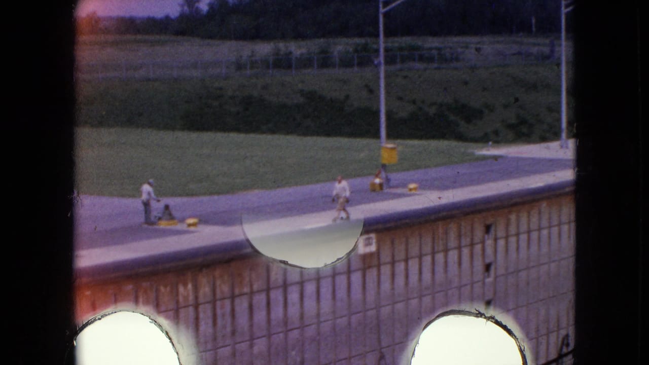 1964 8mm footage from Niagara Falls, New York, showing workers on a concrete canal lock deck beside a docked vessel, with visible light-leak circles and faded color.