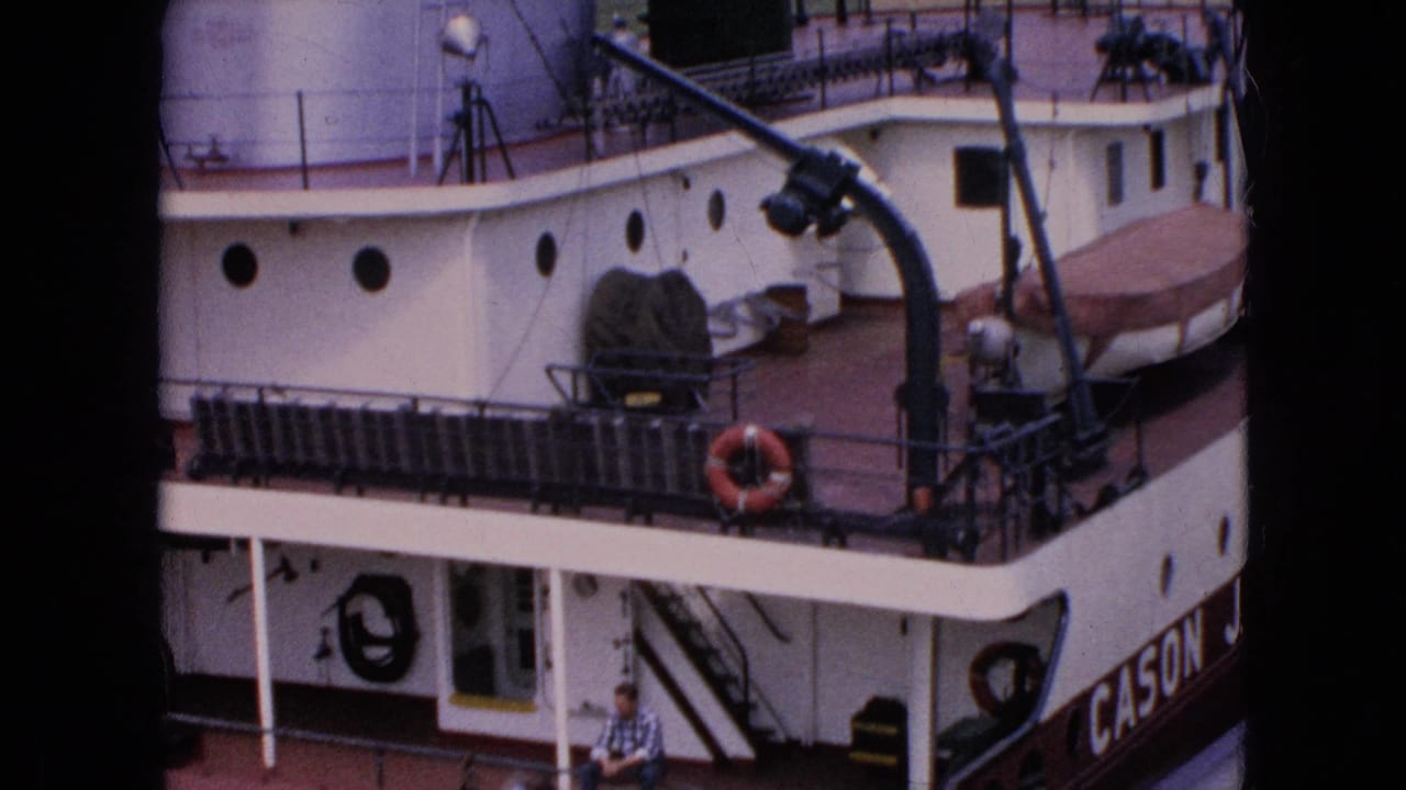1964 Niagara Falls frame showing the Cason J. Callaway riverboat deck from above, with a life preserver, covered lifeboat, railings, and a seated man visible.