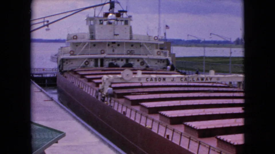 1964 8mm frame of the docked Cason J. Callaway, with cargo hatches leading toward the white superstructure and an adult figure near the railings for scale.