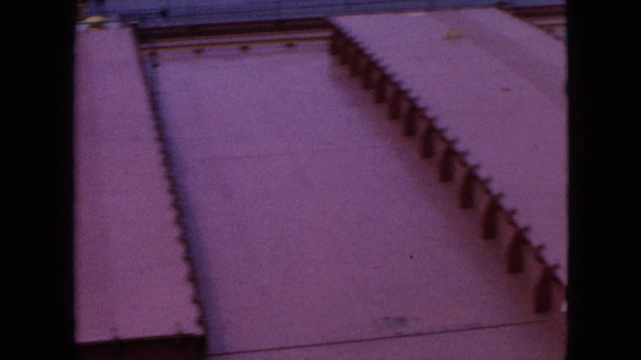 1964 8mm view of a red-painted tanker deck in the United States, showing raised steel ribs, small deck fittings, and a soft handheld home-movie frame.
